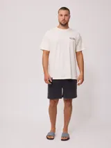 Remera oversize de algodón en color beige, con cuello redondo, manga corta y estampado pequeño en el pecho y diseño grande en la espalda.