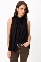 Blusa sin mangas color crema, con cuello alto fruncido y diseño holgado.