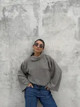 Polera de punto acanalado en color gris, con diseño de cuello abierto lateral, corte recto y mangas amplias.