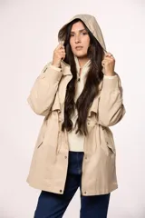Campera tipo trench de nylon color beige, con capucha ajustable, cierre frontal con cremallera y botones a presión, bolsillos laterales con solapa y cordón ajustable en la cintura.