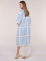 Cardigan largo confeccionado en tejido de punto calado estilo crochet, de color amarillo y blanco, con diseño geométrico de cuadrados, mangas amplias tipo kimono y corte abierto al frente.