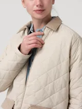 Campera acolchada de nylon con diseño de rombos, cuello de pana en contraste y cierre frontal metálico. Cuenta con bolsillos frontales y un diseño funcional ideal para climas fríos.