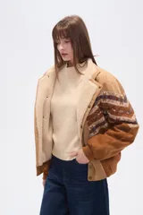 Chaqueta holgada de poliéster en color tostado con forro de corderito, cuello de solapa y cierre frontal con botones. Presenta mangas con apliques de diseño geométrico en tonos marrones y azules.