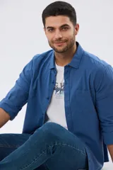 Camisa lisa de manga larga en color azul, confeccionada en mezcla de lino y algodón. Presenta cuello camisero, bolsillo ojal en el pecho, cierre frontal con botones y mangas adaptadas para arremangar.
