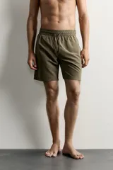 Short de baño largo en color beige, confeccionado en tejido técnico con tacto aterciopelado. Cuenta con cintura elástica ajustable con cordón, bolsillos laterales y detalle de bolsillo trasero, además de forro interior.