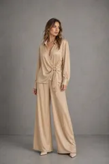 Conjunto compuesto por blusa cruzada de manga larga con detalle de hebilla lateral y pantalón estilo wide leg de tiro alto, confeccionados en tejido texturizado en tono arena.