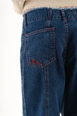 Pantalón de jean azul de corte recto y tiro medio, con costuras decorativas en contraste y bordado exclusivo en la parte frontal.
