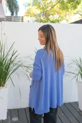 Sweater de punto color celeste, de corte holgado y largo, con mangas largas, cuello redondo y dos bolsillos frontales tipo parche.