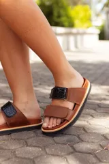 Sandalias de cuero color marrón con dos tiras ajustables, una de cuero liso y otra con textura de cocodrilo en color negro.