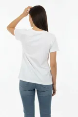 Remera de algodón negra con cuello redondo y mangas cortas. Presenta un estampado frontal con la frase 'WANTED AND WILD', gráficos de revólveres, estrellas y texto alusivo a un festival western.