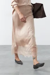 Falda midi negra de caída fluida con cintura elastizada y un amplio detalle de encaje negro en el bajo.