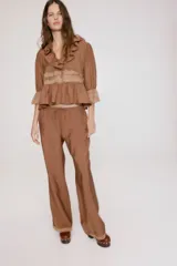 Pantalón de pierna recta color marrón con leve brillo, cintura elástica con cordón ajustable y ribetes de encaje en los bajos.