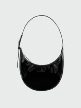 Cartera tipo hobo de Longchamp, modelo Le Roseau S, confeccionada en cuero charol negro con acabado brillante. Presenta una forma de media luna, cierre superior con cremallera y una correa ajustable para el hombro.