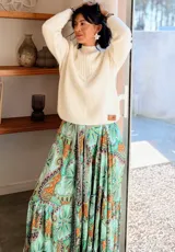 Sweater de punto color blanco, con cuello alto y detalle de escote en V con flecos decorativos. Presenta mangas largas con puños ajustados y un diseño de tejido acanalado en la parte superior.