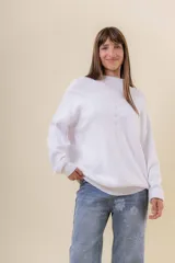 Sweater tejido de punto color blanco, con cuello alto y diseño en relieve tipo chevron en la parte frontal. Presenta un calce holgado con terminaciones acanaladas en puños y ruedo.