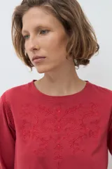 Remera de manga larga color rojo, con cuello redondo y detalle de bordado floral en el pecho.