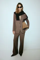 Blazer largo de color marrón, con solapas de muesca, botonadura sencilla y dos bolsillos delanteros con solapa. Presenta forro interior.