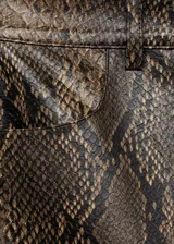 Falda corta de tiro medio con diseño recto y efecto piel de serpiente. Cuenta con trabillas para cinturón, dos bolsillos laterales y cierre frontal con cremallera y botón.