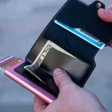 Billetera tipo tarjetero de cuero negro con caja de aluminio interna y sistema de deslizamiento para tarjetas. Cuenta con cierre mediante broche a presión.