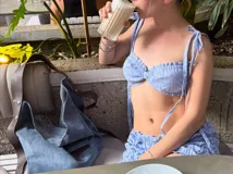 Top corto de estilo bralette con estampado de rayas verticales finas en color celeste y blanco. Presenta un diseño fruncido en el centro del busto y breteles finos que se atan en los hombros.