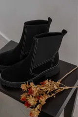 Botas de caña media confeccionadas en gamuza y neopreno, con suela track de goma y costuras a la vista en color blanco.