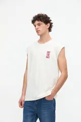 Musculosa de algodón color blanco off-white, de corte relajado, con cuello redondo y estampa pequeña en el pecho con texto en color bordó.