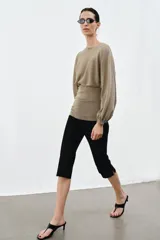 Cuerpo de punto con cuello redondo y mangas largas abullonadas. Presenta un diseño con cintura entallada y bajo ajustado.