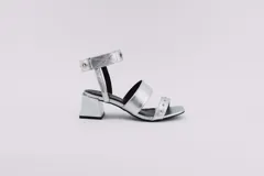 Sandalias negras de cuero con dos tiras horizontales sobre el pie y pulsera al tobillo con ojalillos y tachas. Taco cuadrado de 5 cm.