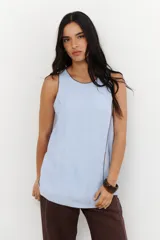 Musculosa color crudo con cuello redondo y ribete marrón en cuello, sisas y ruedo. Diseño cruzado en el frente y aberturas laterales.