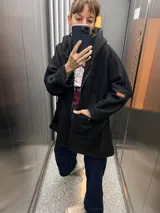 Campera oversize de textura tipo corderito, color marrón, con capucha, cierre frontal completo y dos bolsillos delanteros tipo parche con etiqueta de marca.