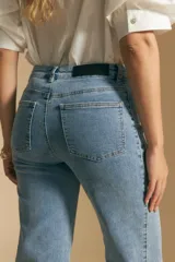 Jean de corte recto y tiro medio, confeccionado en denim elastizado de color negro. Presenta un diseño clásico con cierre de botón y cremallera, bolsillos laterales y traseros, y ruedo con terminación deshilachada.