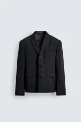 Blazer de corte relajado confeccionada en tejido con mezcla de lana. Presenta cuello con solapas de muesca, cierre frontal de tres botones, bolsillos con solapa en la cadera y un bolsillo en el pecho. Cuenta con manga larga con puños abotonados y aberturas en la espalda.