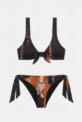Conjunto de bikini color negro con estampado de tigres y palmeras, compuesto por un top de tirantes anchos con nudo central y una bombacha tipo vedetina con tiras laterales ajustables para atar con lazos.