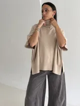 Poncho de tejido de punto color marrón chocolate, con cuello alto tipo polera y mangas cortas amplias. Presenta un diseño holgado con terminaciones acanaladas en el ruedo.