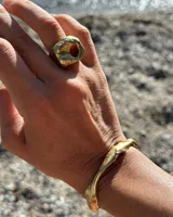 Anillo dorado con forma irregular y un agujero en el centro.
