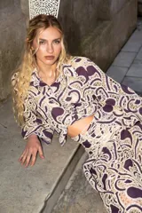 Camisa de guipur color morado con diseño de encaje en contraste de tono crudo, cuello clásico, mangas largas y cierre frontal con botones ocultos.