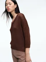Sweater de punto con brillo, de corte relajado y escote en V. Presenta hombros caídos y mangas largas con puños acanalados.