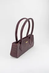 Cartera tipo baguette color negro con textura efecto cocodrilo, diseño alargado, doble asa de mano y cierre superior.