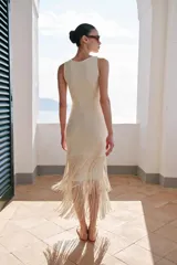 Vestido midi de escote redondo y sin mangas, confeccionado en tejido con textura. Presenta un diseño recto con bajo acabado en capas de flecos largos al tono.