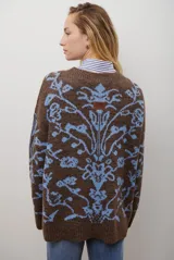 Buzo de tejido de punto en color marrón con un patrón ornamental floral en color celeste. Presenta cuello redondo, mangas largas y un corte holgado.