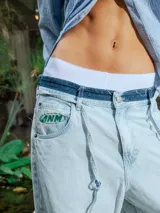 Pantalón de jean celeste lavado, de corte ancho y tiro alto con cordón ajustable en la cintura. Presenta detalles deshilachados en los bajos.