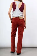 Pantalón de pana tiro alto color óxido, de corte flare y pierna ancha. Cuenta con botonadura frontal metálica y bolsillos plaqué delanteros.