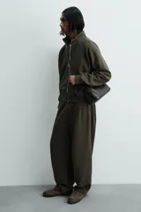 Bolso bandolera negro de piel con textura, cierre de solapa con imán y cremallera. Incluye bolsillo interior con cremallera y bolsillo plano. Asa de hombro ajustable de piel.