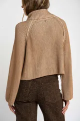 Sweater marrón de punto acanalado, con cuello alto, cierre frontal parcial con cremallera y manga larga.