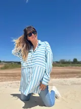 Camisa oversize celeste con rayas verticales blancas, de manga larga y cuello clásico.