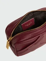 Cartera crossbody de cuero negro con diseño rectangular, cierre superior y correa de cadena dorada. Presenta el detalle de una estrella característica de la marca grabada en el frente.