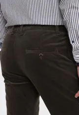 Pantalón de pana gris con corte slim fit, bolsillos laterales y traseros, y cinturón trenzado verde.