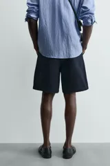 Bermuda de hombre color azul marino, de corte relajado (relaxed fit), confeccionada en tejido con textura. Presenta bolsillos frontales y bolsillos traseros de vivo, con cierre frontal de cremallera y botón.