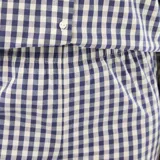 Pijama de dos piezas confeccionado en popelina con estampado de cuadros vichy. Incluye una camisa de manga larga con cuello camisero, cierre frontal de botones y puños con volados, y un pantalón de corte recto con terminación de volado en el ruedo.