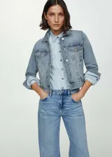 Chaqueta de denim celeste, con diseño corto, cuello de solapa, cierre frontal de botones metálicos, bolsillos frontales con solapa y bolsillos laterales ribeteados.